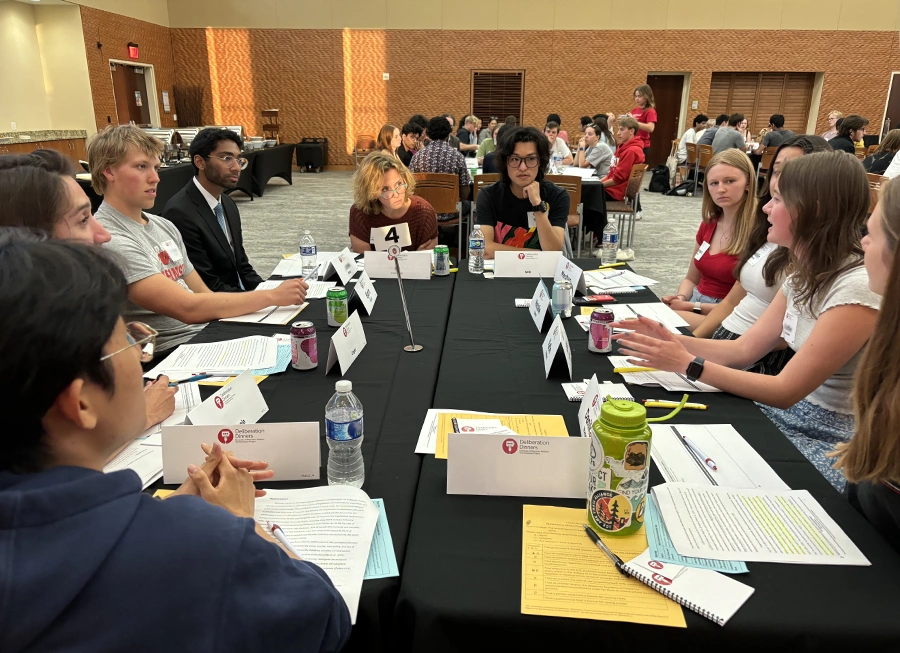 Ten people at a table. One person is talking and everyone at the table is looking at them.