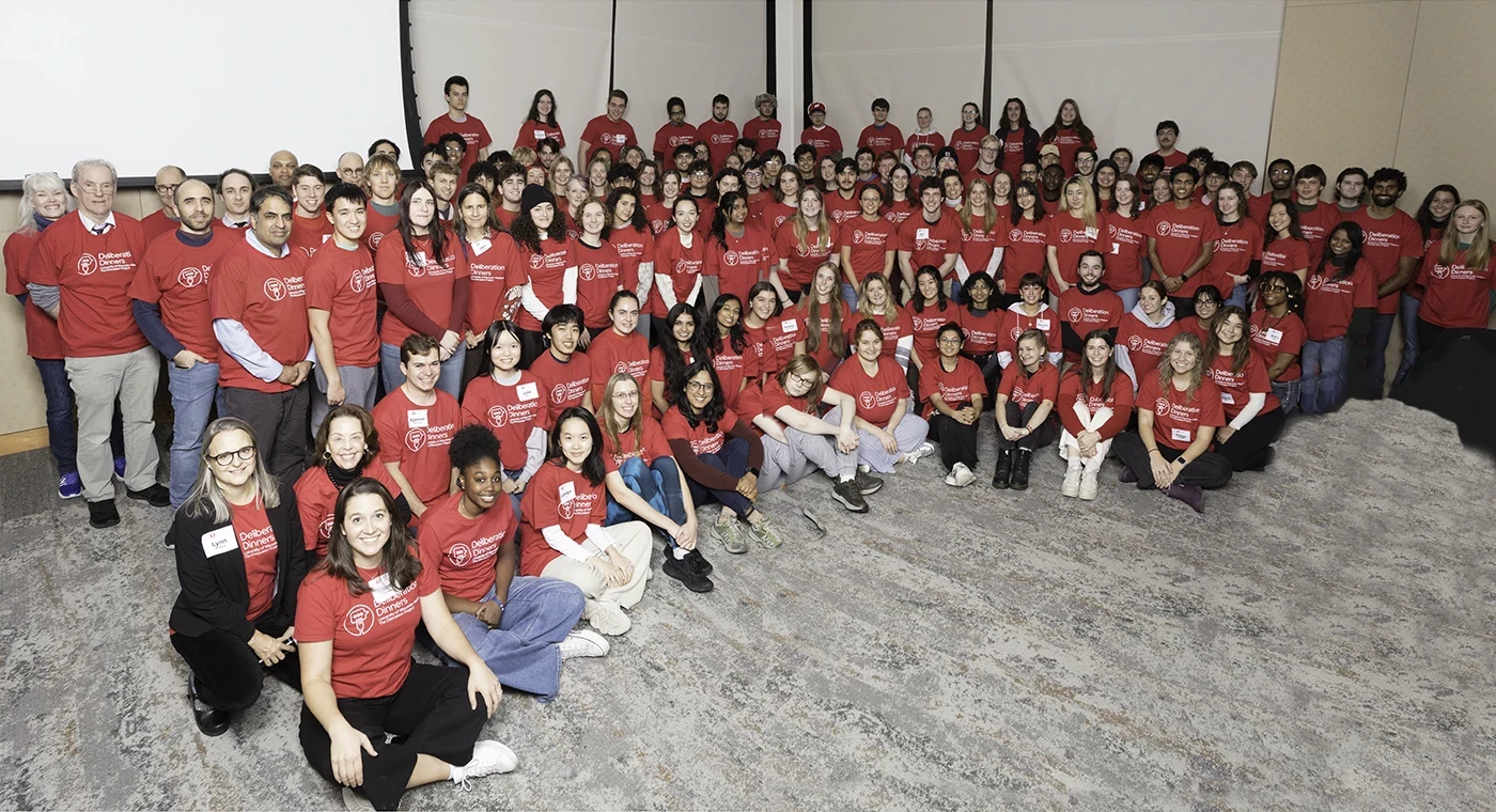 Large group photo with everyone wearing the red Deliberation Dinners shirts.