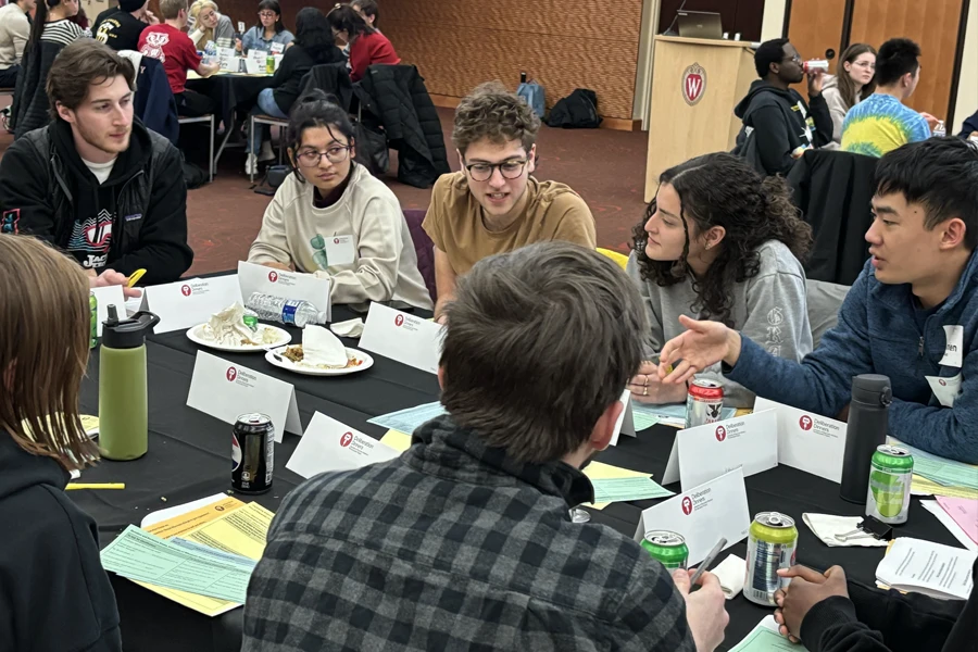 A group of seven students having a discussion at a table.