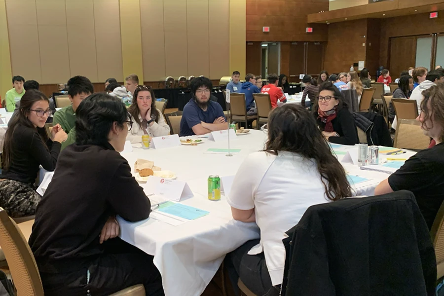 A group of students sitting around a table with a facilitator.